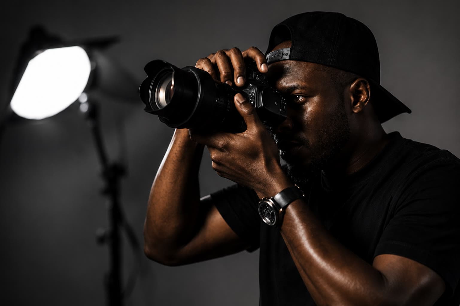 Photographer at the eyepiece with a long lens, a softbox lighting him from the left